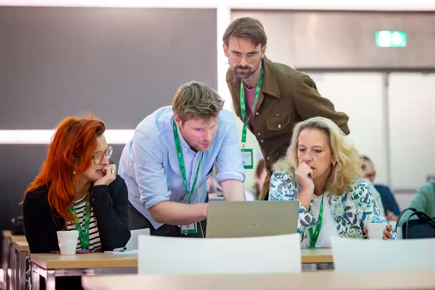 Matthijs Mentink kijkt mee op de laptop van deelnemers tijdens een training, met Jim van Oosten erbij
